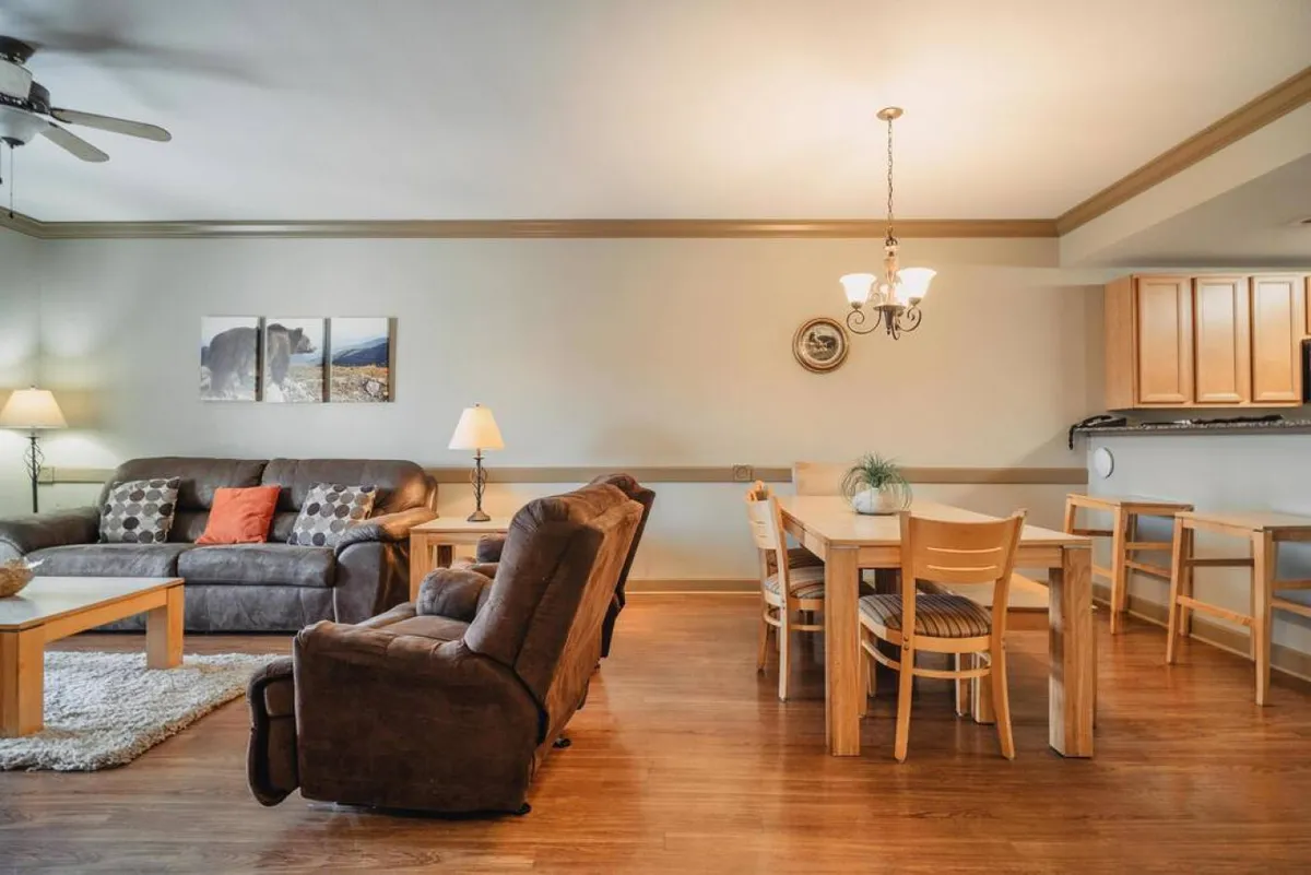 A welcoming space with a sofa, dining table, light fixture, and wall art. The open-plan layout and uncluttered arrangement make it easy to navigate, supporting inclusive gatherings and family accessibility.